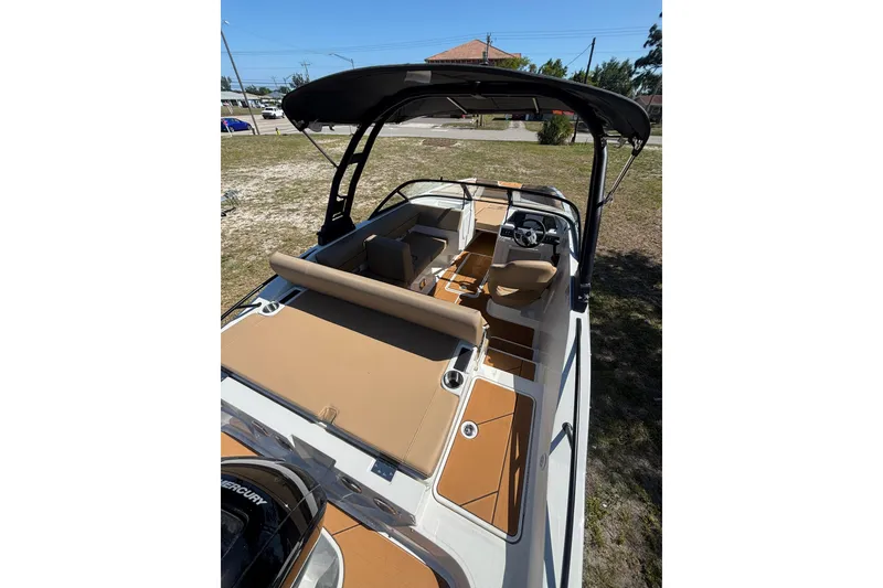 Slide: The Image of 2026 Bayliner D20 boat with tan seating and black canopy, parked on grass. - 5