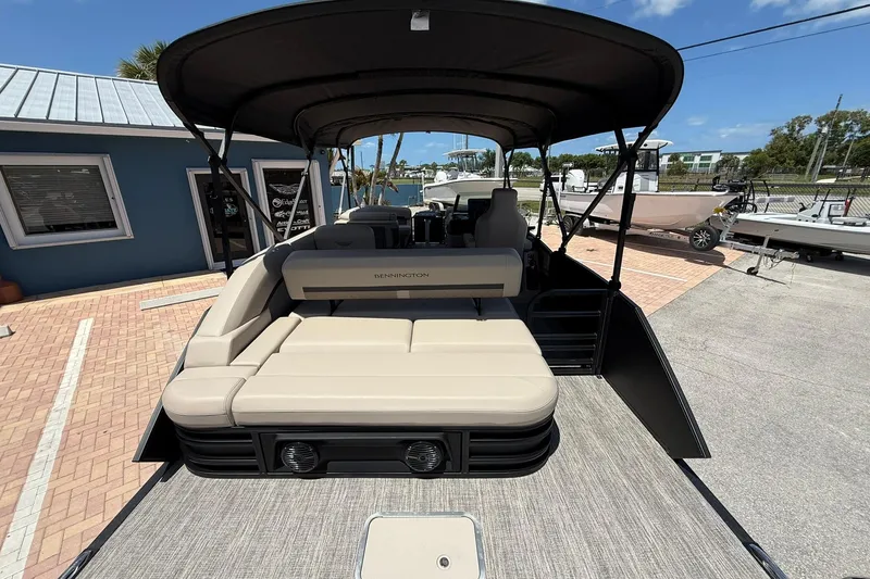 Slide: The Image of 2026 Bennington 22 M Swingback pontoon boat with beige seating and canopy, parked outdoors. - 5