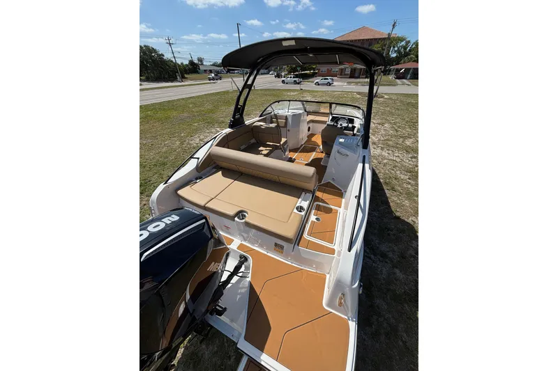 Slide: The Image of 2026 Bayliner D22 boat with tan seating and black canopy, parked on grass. - 10