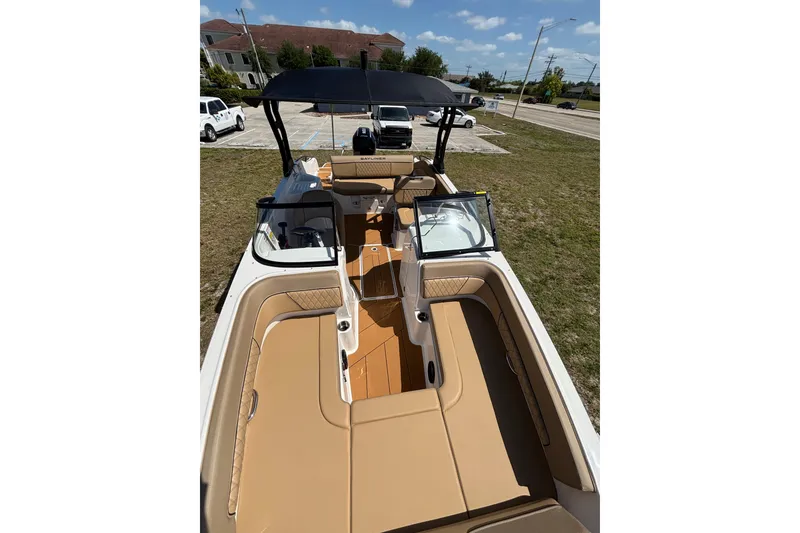 Slide: The Image of 2026 Bayliner D22 boat with tan seating and black canopy, parked on grass. - 19