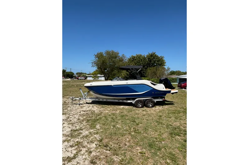Slide: The Image of 2026 Bayliner D22 boat on trailer, parked on grassy area under clear blue sky. - 5