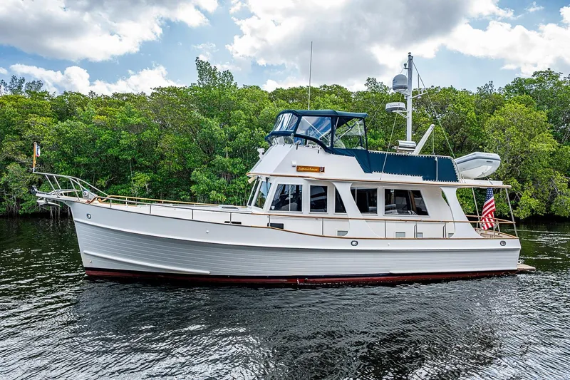 The Image of 2002 Grand Banks 42 Europa yacht on calm water, surrounded by lush greenery. - 0