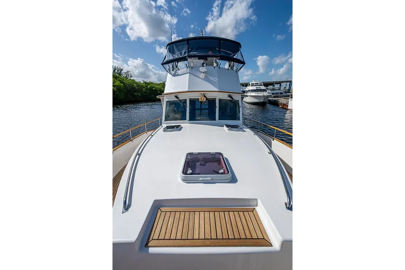 Slide: The Image of 2002 Grand Banks 42 Europa yacht on water, showcasing sleek deck design under blue sky. - 16