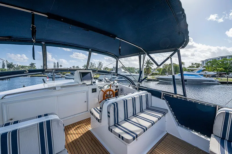 Slide: The Image of Flybridge of 2002 Grand Banks 42 Europa yacht with striped seating and scenic marina view. - 24