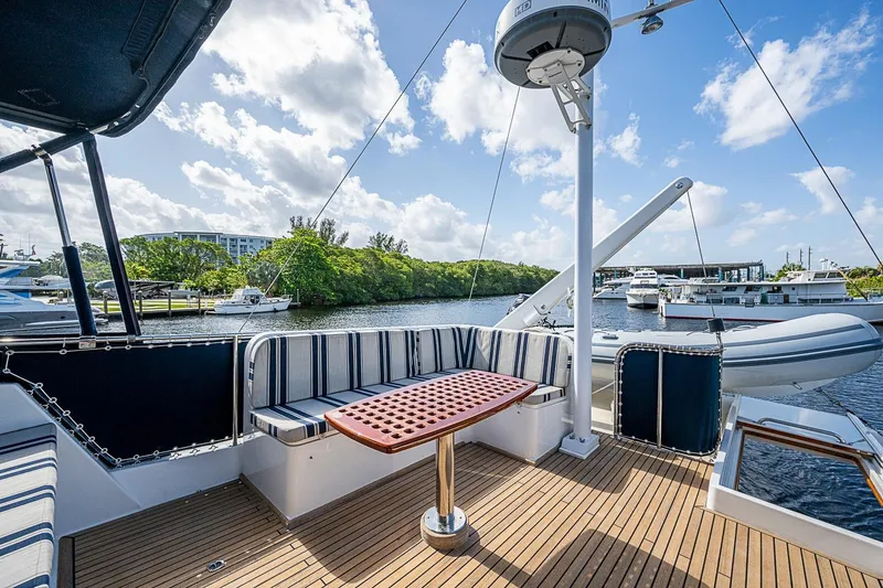 Slide: The Image of Deck view of 2002 Grand Banks 42 Europa yacht with seating and table, docked by water. - 26