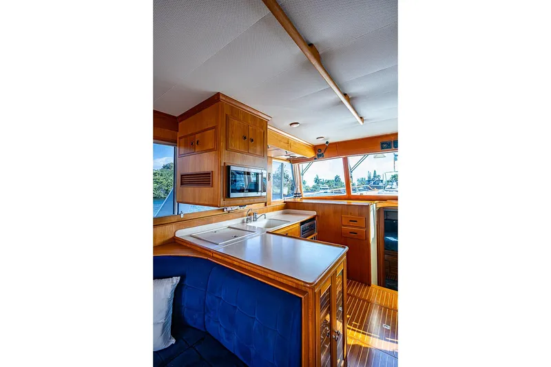 Slide: The Image of Interior of 2002 Grand Banks 42 Europa yacht, featuring a wooden kitchen and seating area. - 34