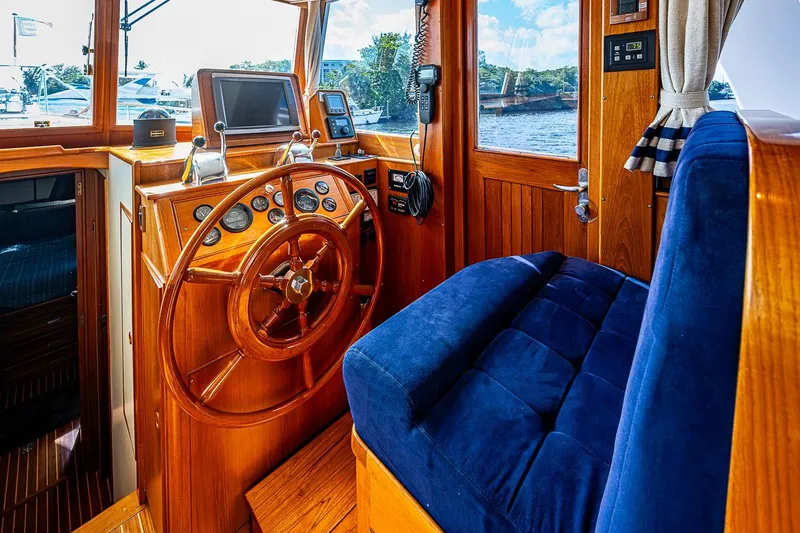 Slide: The Image of Interior helm of 2002 Grand Banks 42 Europa yacht with wooden steering wheel and blue seating. - 39