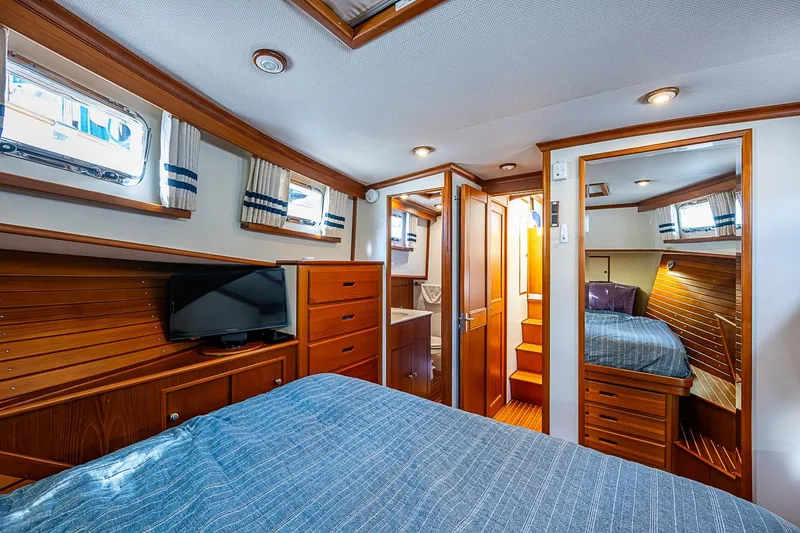 Slide: The Image of Luxurious cabin interior of 2002 Grand Banks 42 Europa yacht with wood finishes and cozy bedding. - 44