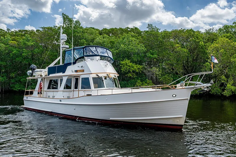 Slide: The Image of 2002 Grand Banks 42 Europa yacht cruising on a serene waterway with lush greenery. - 5