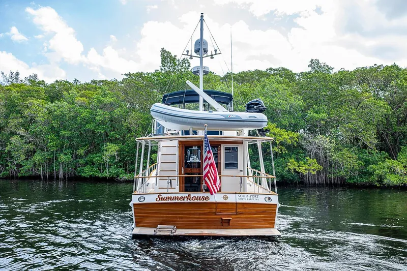 Slide: The Image of Grand Banks 42 Europa yacht, 2002 model, cruising on a serene river with lush greenery. - 56