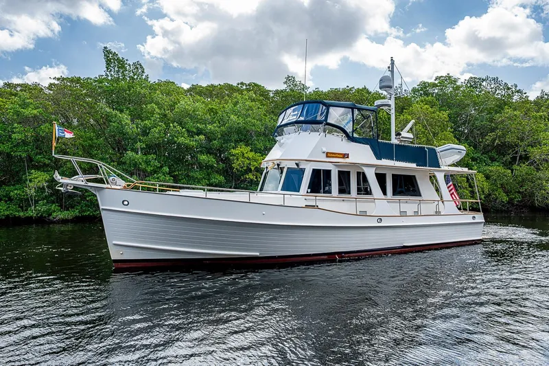 Slide: The Image of 2002 Grand Banks 42 Europa yacht cruising on a serene river with lush greenery. - 58