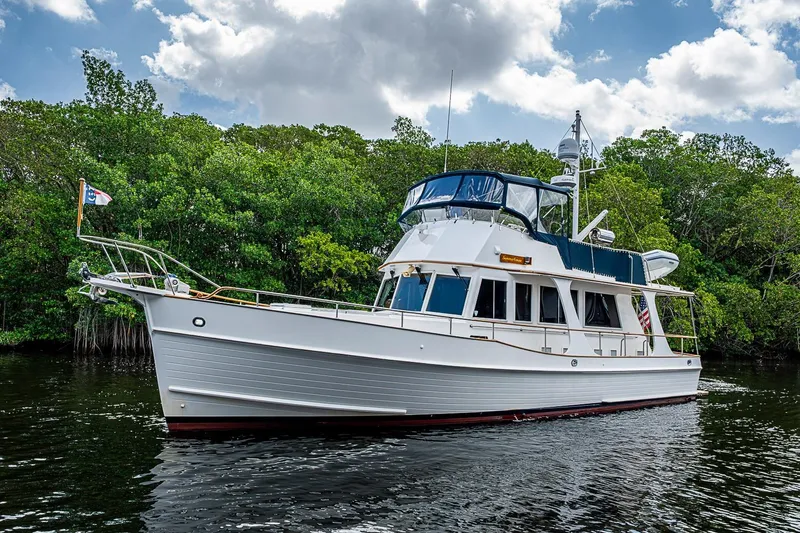 Slide: The Image of Grand Banks 42 Europa 2002 yacht cruising on a serene waterway with lush greenery. - 6