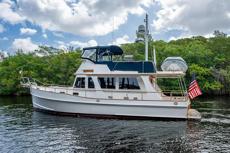 Slide: The Image of 2002 Grand Banks 42 Europa yacht on calm water, surrounded by lush greenery. - 7