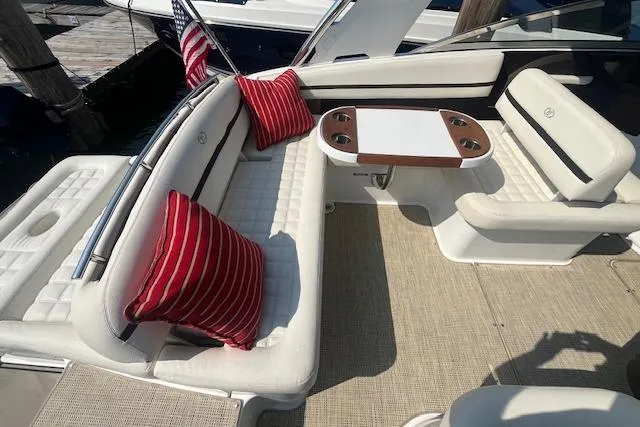 Slide: The Image of 2018 Cobalt R5 boat interior with white seating, red pillows, and a wooden table. - 7