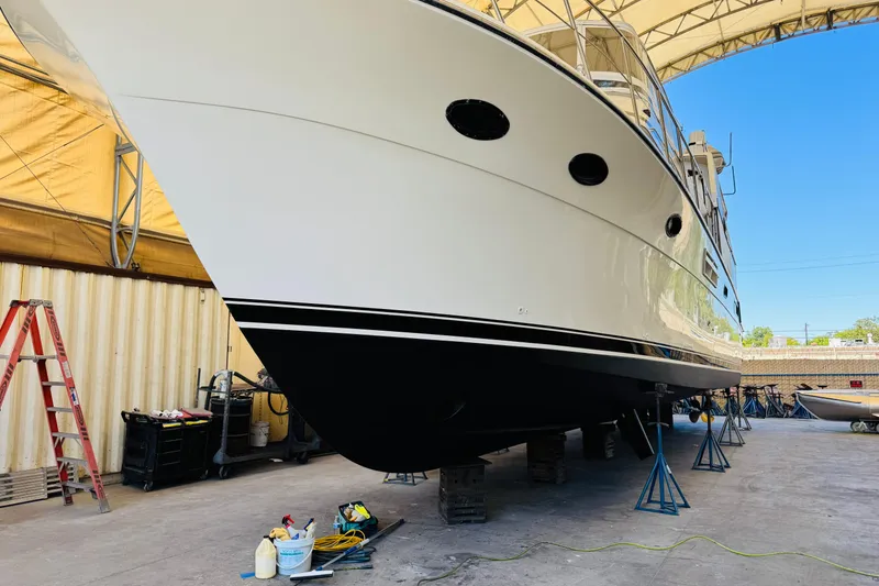 Slide: The Image of 1991 Californian 55 Cockpit Motor Yacht in dry dock for maintenance under a canopy. - 115