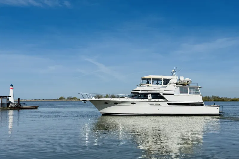 Slide: The Image of 1991 Californian 55 Cockpit Motor Yacht on calm water near a small lighthouse. - 12