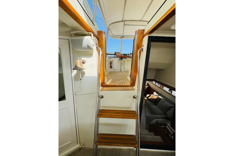 Slide: The Image of Interior view of 1991 Californian 55 Cockpit Motor Yacht with wooden stairs and seating area. - 38
