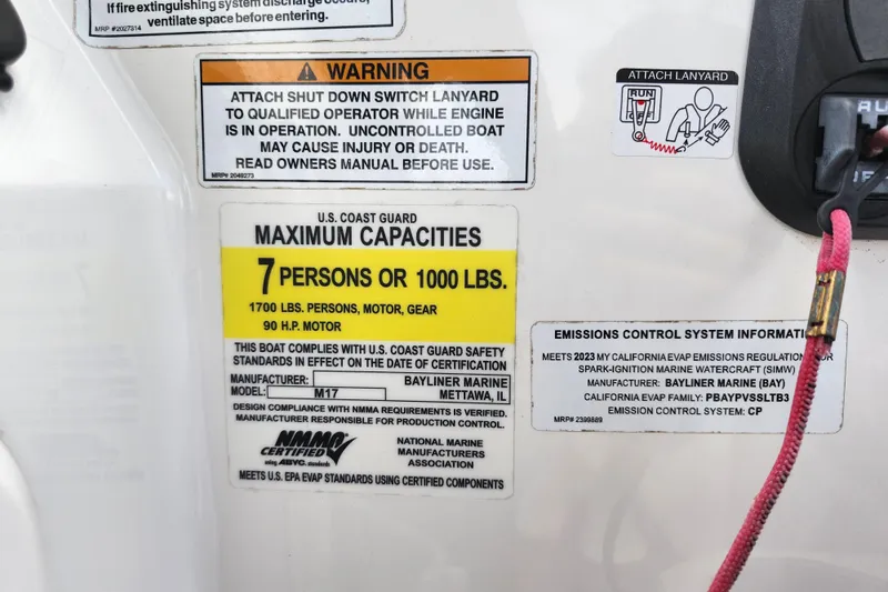 Slide: The Image of Warning and capacity labels on 2023 Bayliner Element M17 boat, detailing safety and emissions information. - 19