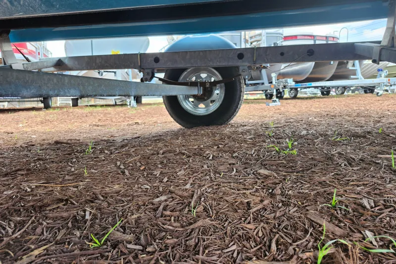 Slide: The Image of Underneath view of a 2023 Bayliner Element M17 boat trailer on mulch ground. - 39