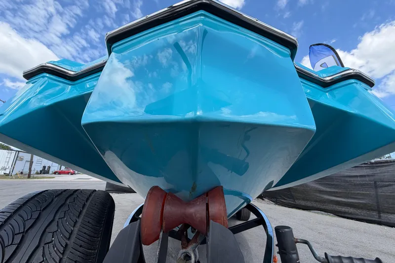 Slide: The Image of 2023 Heyday WTSurf boat hull, vibrant blue, parked on trailer under clear sky. - 12