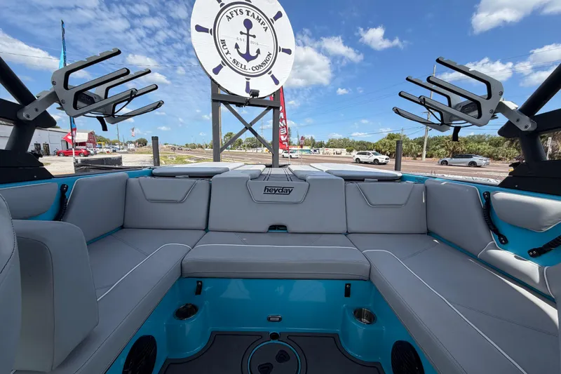 Slide: The Image of 2023 Heyday WTSurf boat interior with gray seating and blue accents under a clear sky. - 28