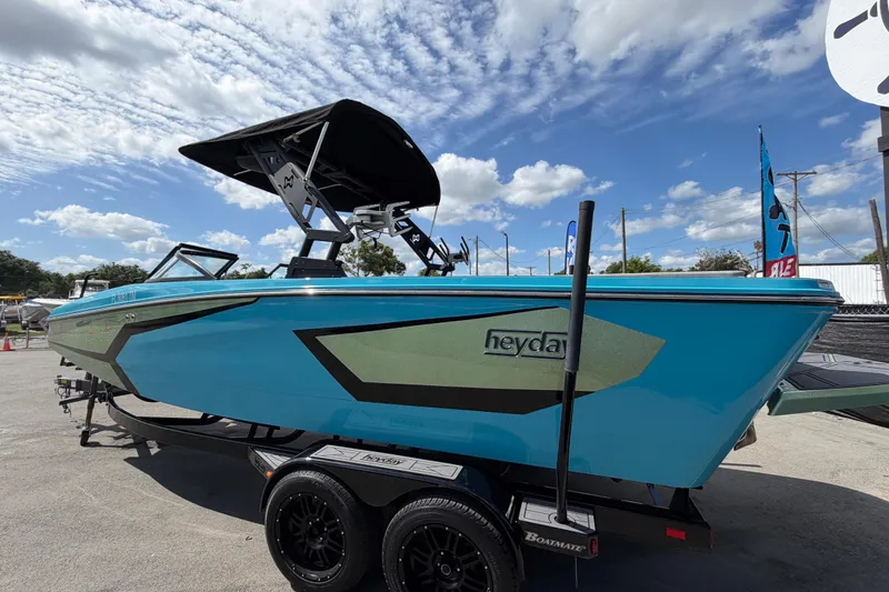 Slide: The Image of 2023 Heyday WTSurf boat in vibrant blue on trailer under a partly cloudy sky. - 8