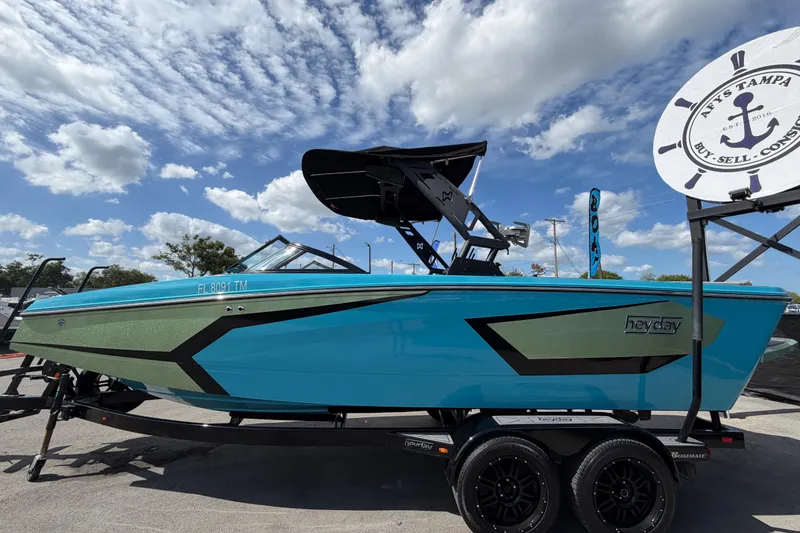 Slide: The Image of 2023 Heyday WTSurf boat in vibrant blue on a trailer under a partly cloudy sky. - 9