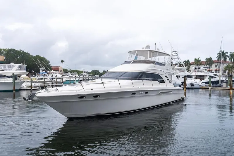 Slide: The Image of 2000 Sea Ray 560 Sedan Bridge yacht docked in a marina, surrounded by other boats. - 2