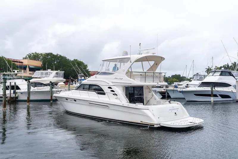 Slide: The Image of 2000 Sea Ray 560 Sedan Bridge yacht docked in a marina, surrounded by other boats. - 4