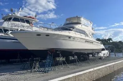 Slide: The Image of 2000 Sea Ray 560 Sedan Bridge yacht on dry dock under a clear blue sky. - 49