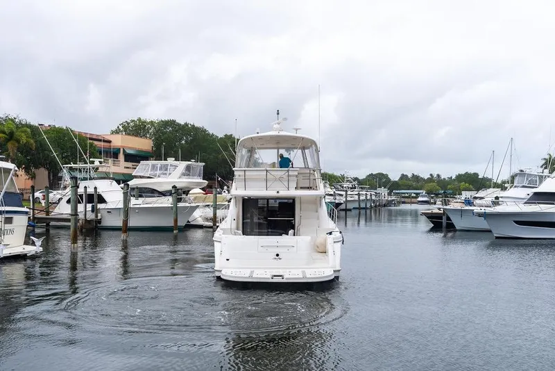 Slide: The Image of 2000 Sea Ray 560 Sedan Bridge yacht navigating a marina, surrounded by other boats. - 5