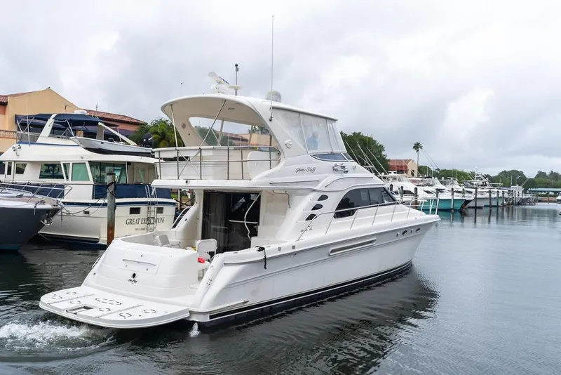 Slide: The Image of 2000 Sea Ray 560 Sedan Bridge yacht docked in a marina, surrounded by other boats. - 6