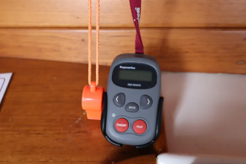 Slide: The Image of Remote control device on wooden surface, featuring buttons and lanyard, model Sydney 38, year 2000. - 25