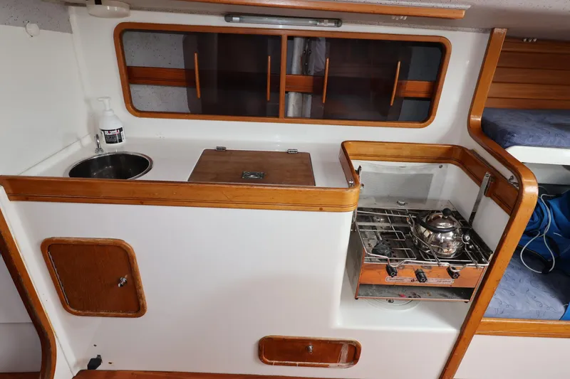 Slide: The Image of Compact galley kitchen in a 2000 Sydney 38 sailboat, featuring a sink and stove. - 29