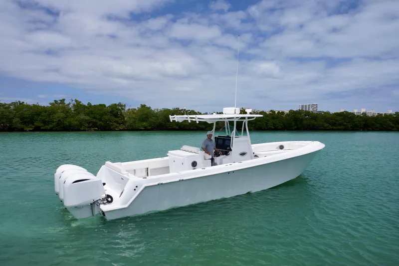 The Image of 2013 Contender 35 LS boat on turquoise water, clear sky, lush green shoreline. - 1