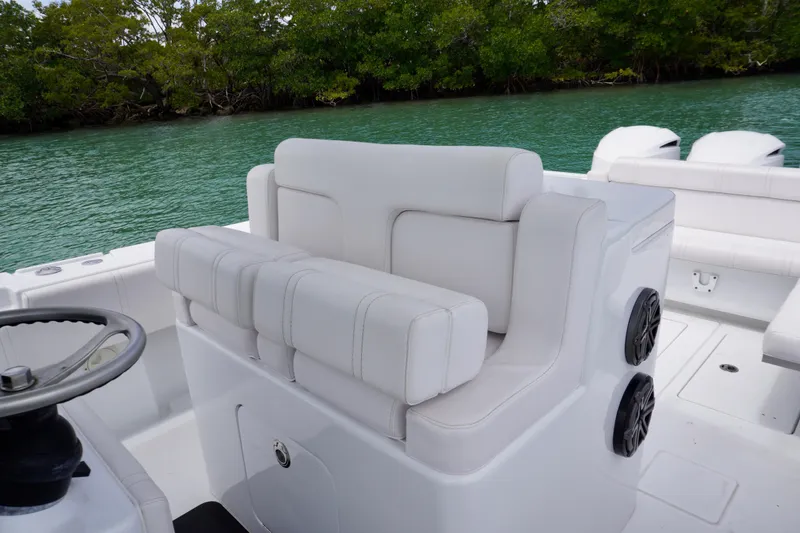 Slide: The Image of 2013 Contender 35 LS boat interior with white seating and steering wheel, near lush greenery. - 20