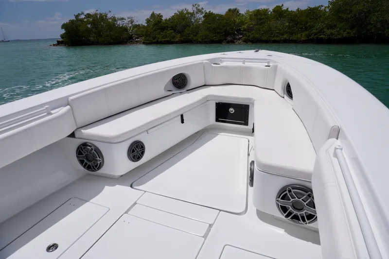 Slide: The Image of 2013 Contender 35 LS boat interior with white seating and speakers, near lush shoreline. - 26