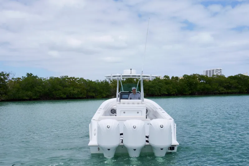 Slide: The Image of 2013 Contender 35 LS boat with triple engines on calm water, surrounded by greenery. - 4