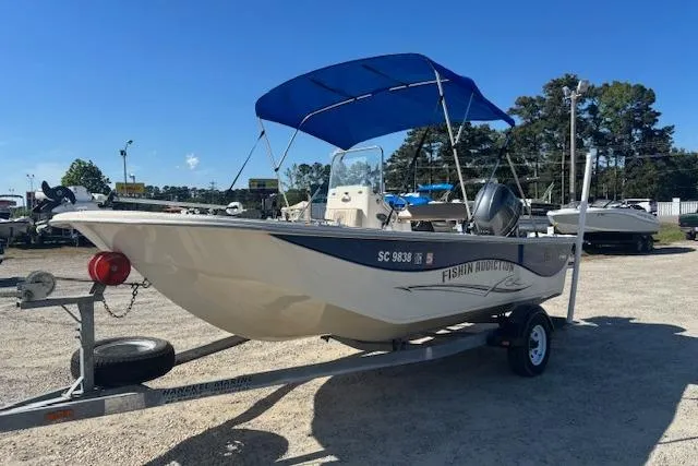 The Image of 2015 Carolina Skiff 198 DLV boat with blue canopy on trailer, parked outdoors. - 0