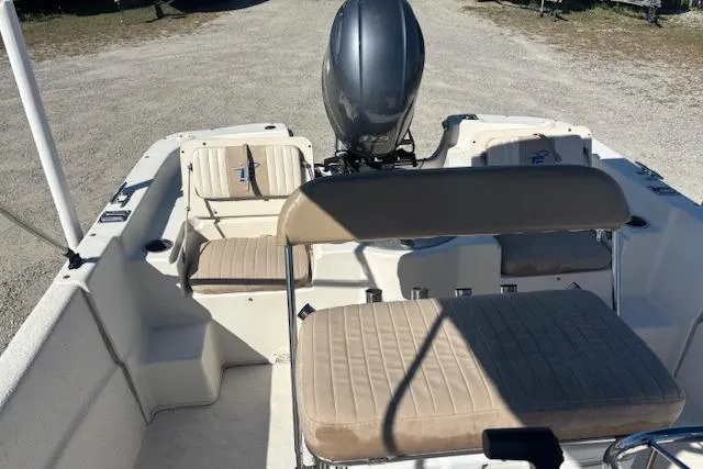 Slide: The Image of 2015 Carolina Skiff 198 DLV boat interior with seating and motor, parked on gravel. - 11