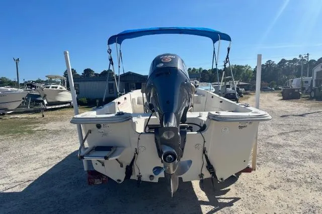 Slide: The Image of 2015 Carolina Skiff 198 DLV boat with outboard motor and blue canopy, parked on gravel. - 5