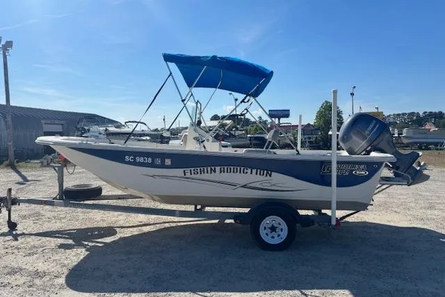 Slide: The Image of 2015 Carolina Skiff 198 DLV boat with blue canopy on trailer, labeled "Fishin Addiction." - 7