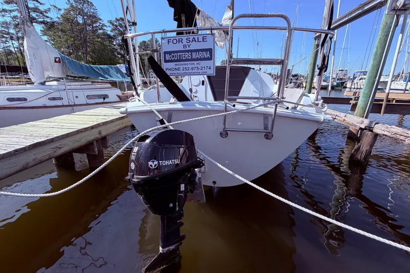 Slide: The Image of 1982 Ericson 25 sailboat for sale at marina dock, featuring Tohatsu outboard motor. - 2
