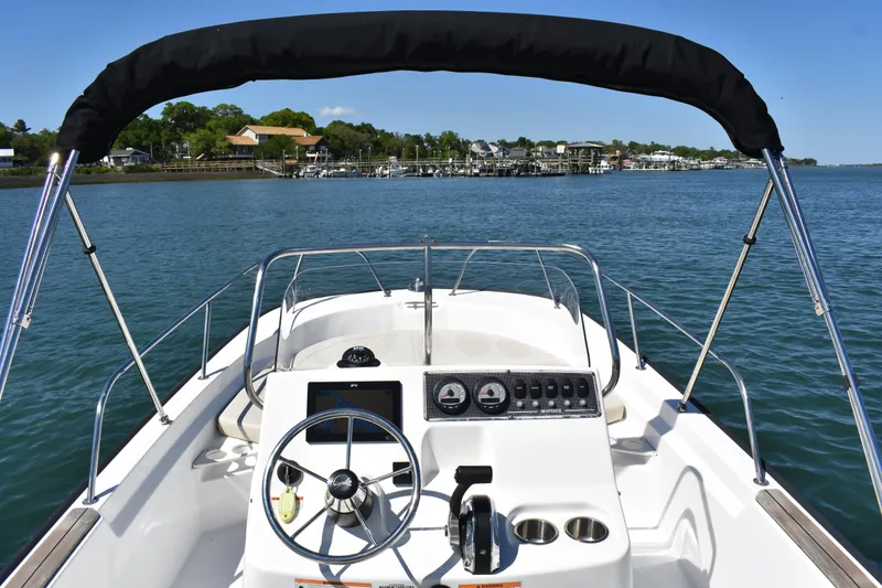 Slide: The Image of 2022 Boston Whaler 190 Montauk boat on calm water with clear sky and shoreline view. - 10