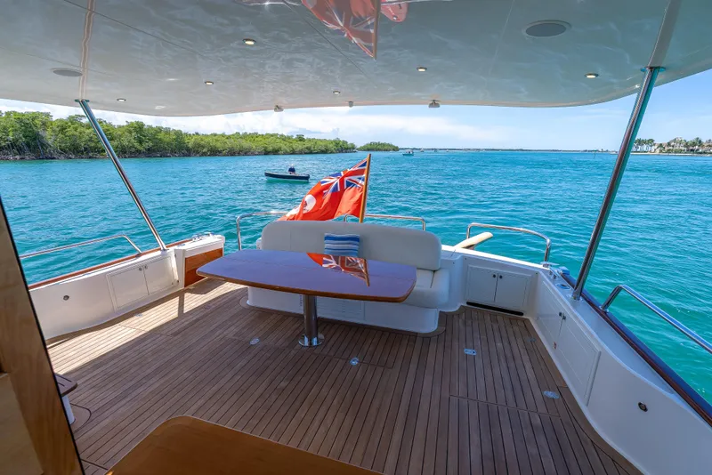 Slide: The Image of 2018 Grand Banks GB60 yacht deck with seating, table, and ocean view. - 11