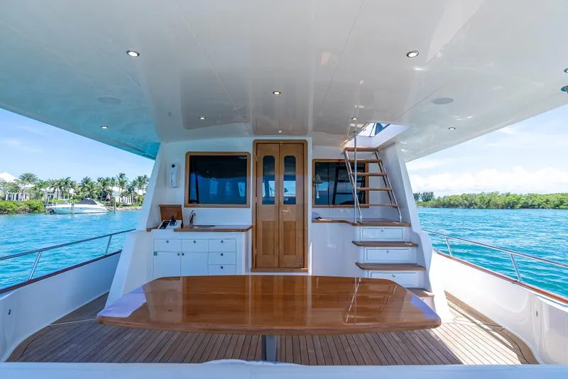Slide: The Image of Luxurious 2018 Grand Banks GB60 yacht deck with wooden table and stairs, overlooking serene waters. - 12