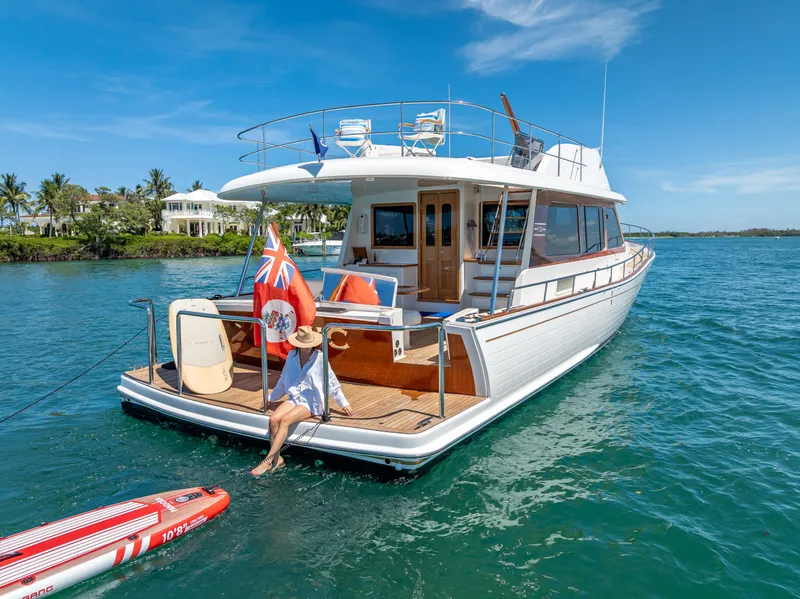 Slide: The Image of 2018 Grand Banks GB60 yacht on serene water with a person relaxing on deck. - 7