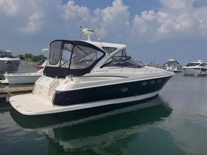The Image of A 2006 Regal Commodore 3860 is docked in the water. It features a black canopy and sleek design. - 0