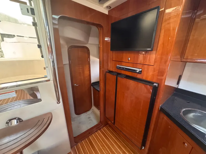 Slide: The Image of The interior cabin of a 2006 Regal Commodore 3860 features a wooden door, TV, and kitchenette. - 26