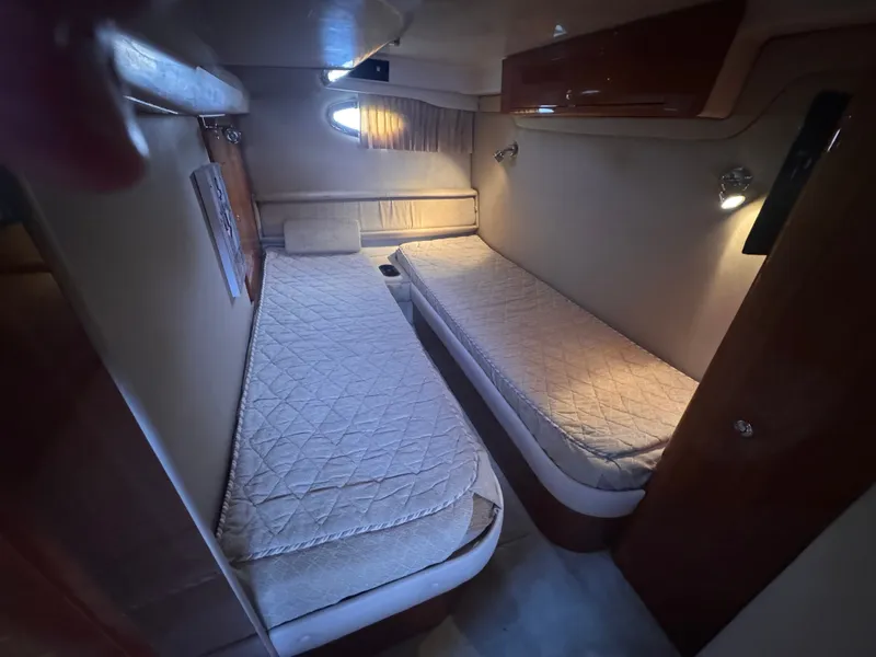 Slide: The Image of The 2006 Regal Commodore 3860 cabin features two single beds, padded walls, and a porthole. - 27